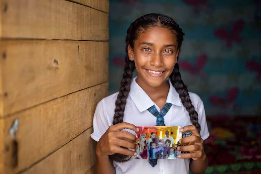 Une jeune fille colombienne montre une photo de ses parrains.
